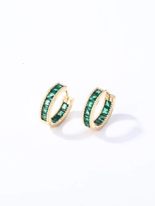 Detalle de pendientes de aro dorados con circonitas verde esmeralda de corte cuadrado
