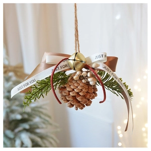 Close-up of a Christmas ornament with natural pine cone, gold bells, and satin ribbon