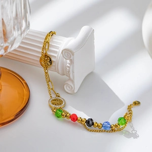 Detailed view of gold tree of life bracelet with colorful beads on a white pillar