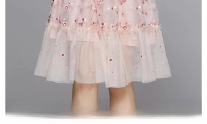 Détail de la robe en tulle rose avec broderie florale 3D et ourlet à volants