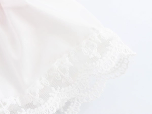 Detail of white striped dress hem showing delicate floral lace trim on soft fabric