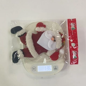 Detailed view of a handmade Santa plush ornament being weighed on a digital scale
