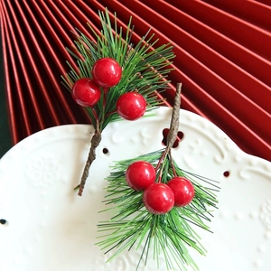 Close-up of decorative Christmas pine needles and red berries on a white ceramic plate