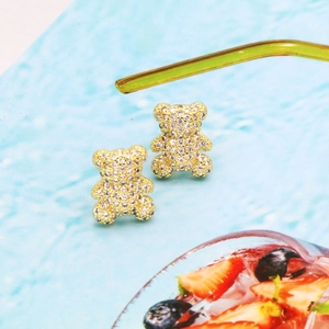 Sparkling gold bear stud earrings with pave cubic zirconia on a fresh blue background