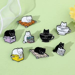 Flat lay of eight cute cartoon cat enamel pins in various poses on a green background
