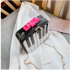 Detail of piano keyboard design mini bag with a pink bow and gold chain strap