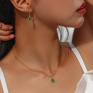 Detail shot of gold necklace and teardrop emerald gemstone pendant set on a model