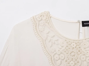 Close-up of elegant ivory blouse neckline with delicate floral lace embroidery and button
