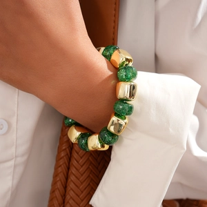 Close-up of green glitter beads and polished gold metal beads on a beaded bracelet