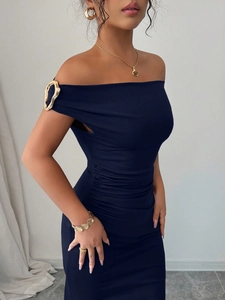 Detail of off-shoulder navy dress featuring irregular gold metal buckle on shoulder