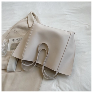 Detail view of large beige leather tote bag with reinforced stitching and long straps