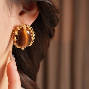 Close-up of vintage gold tiger eye stone earring with detailed textured metal craftsmanship