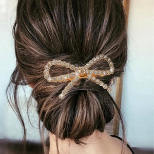 Close-up of sparkling crystal rhinestones on a gold-tone bow hair clip worn on hair