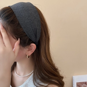 Nahaufnahme eines breiten dunkelgrauen Strick-Stirnbands mit Rippenstruktur am Modell