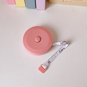 Detail of pink portable measuring tape showing 150cm and 60in scales on a white desk
