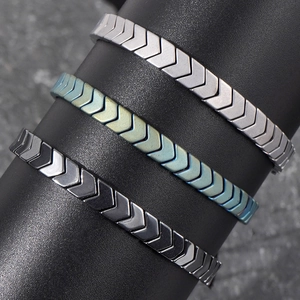 Arrow geometric hematite bracelets in silver, rainbow, and gunmetal on a stand