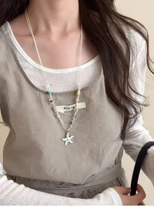 Detail of starfish pendant and natural shell beads on a wax cord necklace strap