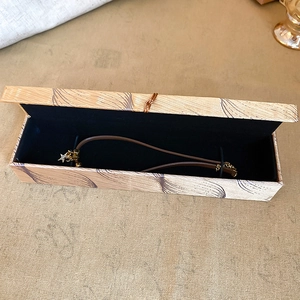Detail of a rectangular jewelry box with velvet lining and a gold star pendant bracelet