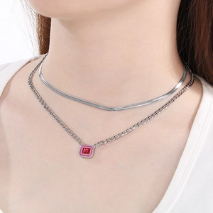 Detail of layered silver necklaces featuring flat snake chain and red square pendant