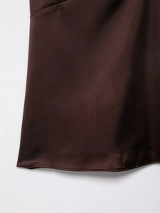 Détail du tissu satiné marron foncé montrant la texture lisse et la couture de l'ourlet