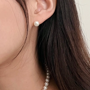 Close-up of 12mm white pearl earrings on model with matching elegant necklace