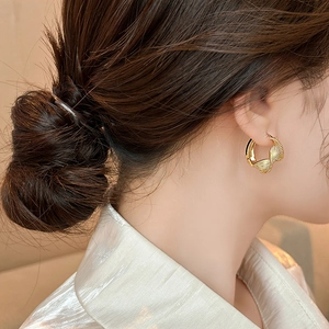Detailed close-up of golden twist hoop earring with textured finish on model