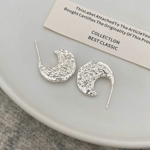 Détail macro de boucles d'oreilles argentées avec texture martelée style lave