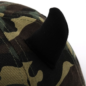 Detail of camouflage baseball cap with black demon horns and pink cross patch texture