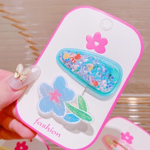 Detail of glitter-filled blue acrylic hair clips with stars and fruits on a pink card