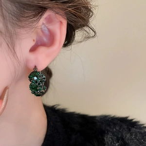 Macro shot of vintage style geometric earrings with green crystals on female model