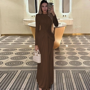 Detail shot of a brown slim-fit long-sleeve knit maxi dress in a cozy indoor setting