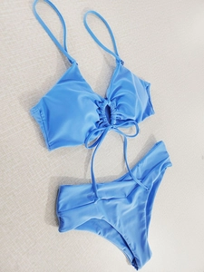 Detailed flat lay of sky blue bikini set with halter bow tie and pleated fabric texture