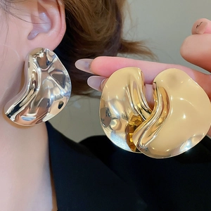 Macro shot of large irregular liquid metal wave earrings in gold and silver finish
