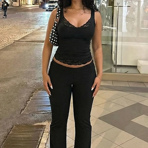 Détail d'un caraco noir avec bordure en dentelle et pantalon évasé assorti chic