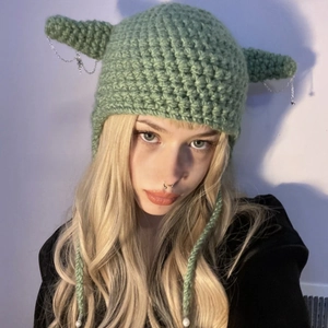 Detail of green crochet knit cat ear beanie featuring silver chains and devil horn design