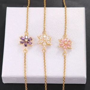 Braccialetti di lusso in oro con fiori di zircone colorati su una base di esposizione bianca
