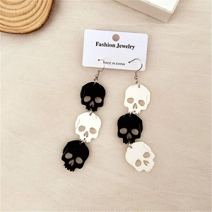 Detail of black and white tiered skull drop earrings on a mesh texture backdrop