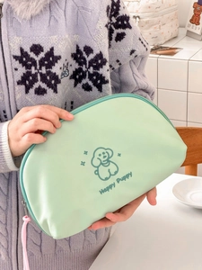 Close-up of light green Happy Puppy makeup bag with zipper and cartoon dog illustration
