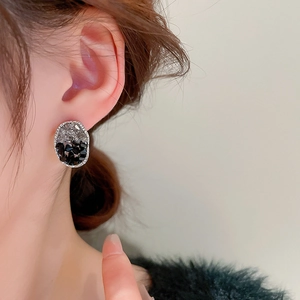 Détail de boucles d'oreilles ovales avec cristaux noirs et clairs sur monture argent