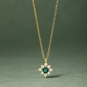 Close-up of a floral S925 silver pendant with green emerald center and sparkling diamonds