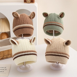 Detail of striped knitted baby hats with bear ears in multiple warm neutral colors