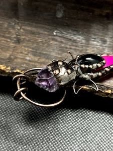 Macro shot of vintage bronze insect pendant with purple amethyst and agate crystal details