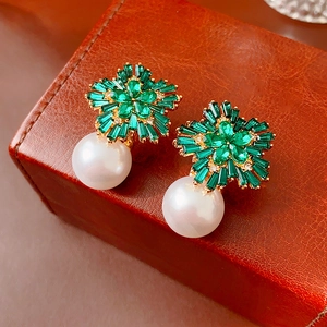 Detail of floral earrings with green emerald-cut stones and white round pearls on leather