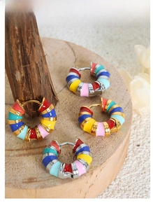 Macro shot of colorful enamel spiral hoop earrings on a natural wood surface background