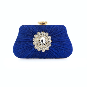 Detail of dark blue pleated clutch with crystal flower clasp and golden crown buckle