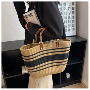 Fashionable woven tote bag featuring black and brown stripes with natural bamboo handles