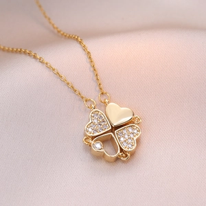Elegant gold-plated four-leaf clover heart necklace with cubic zirconia on satin background