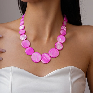 Detail of magenta shell beaded necklace with pearlescent gradient discs on neck