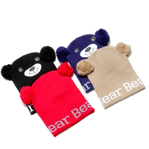 Flat lay of knit bear ear hats in black, blue, red, and khaki with pom-poms and Bear text