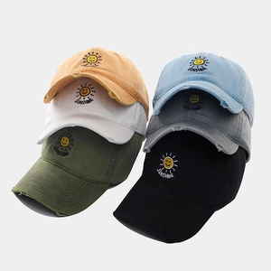 Close-up of vintage washed cotton baseball caps with embroidered sun smiley and frayed brim
